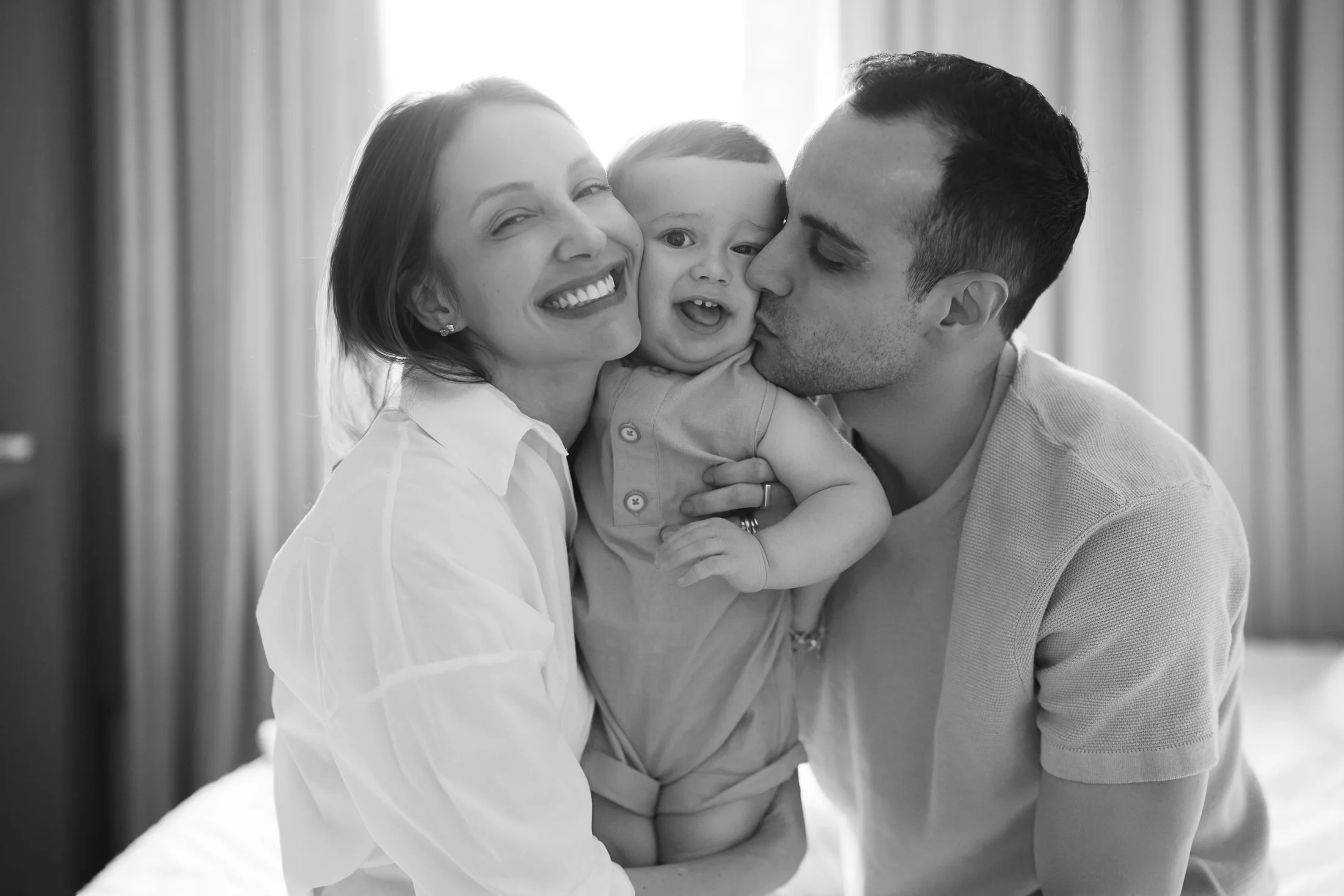 Família sorrindo e acolhendo o bebê em preto e branco